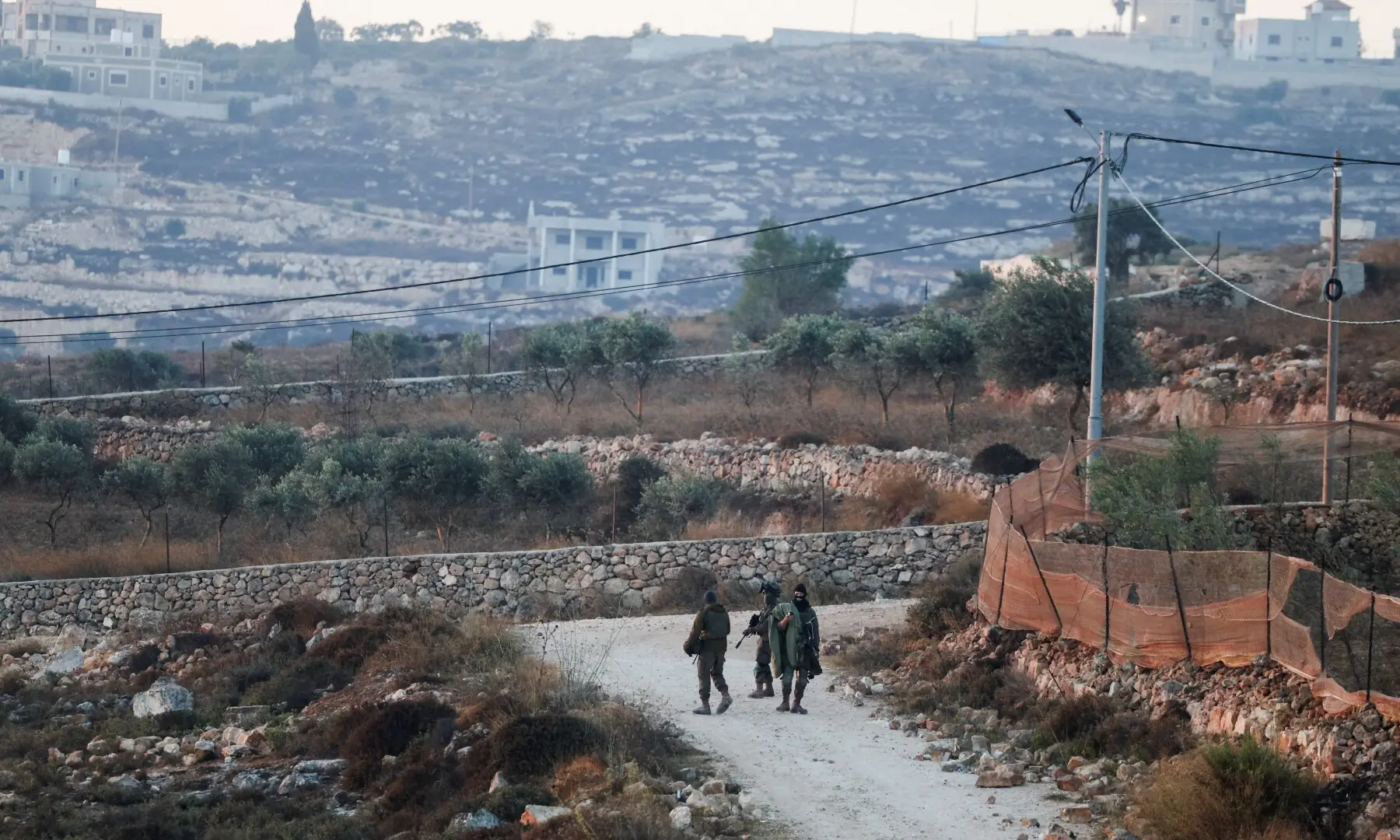 Israeli soldiers walk near the home of Palestinian-American Loui Ridi, which has been encircled by militant settlers for more than a week, after Ridi gained access to it, in Qusra, Israeli-occupied West Bank on August 18, 2026. &mdash;Reuters