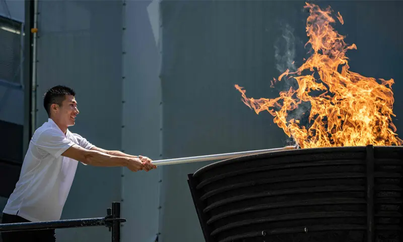Japanese sprinter Yoshihide Kiryu lights the torch from the Olympic cauldron during the torch lighting ceremony for the Asian Games, outside the National Stadium on Tuesday.&mdash;AFP
