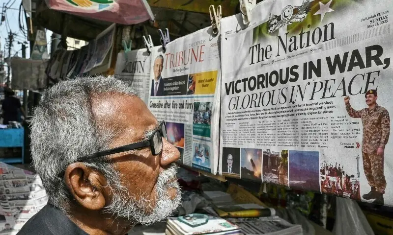 A resident reads a morning English newspaper on a roadside stall in Karachi on May 11, 2025. &mdash; AFP/File