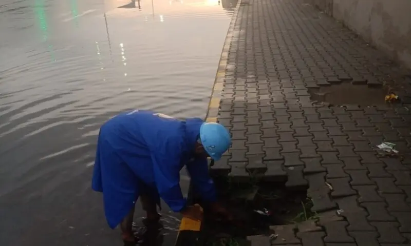 This image shows a worker attempting to clear rainwater accumulated on a road in Rawalpindi. &mdash; Photo provided by author