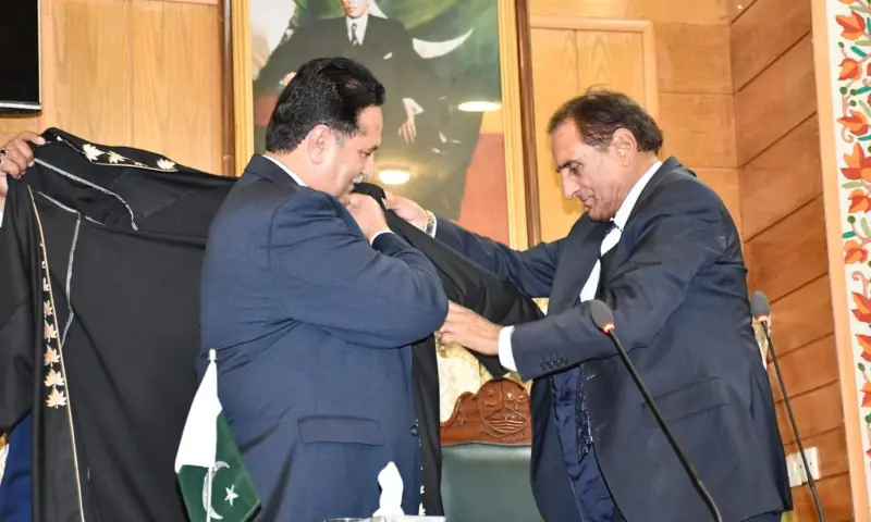 Outgoing Speaker Chaudhry Latif Akbar (right) helps his successor Chaudhry Tariq Farooq put on the speaker's robe after administering him the oath during a session of the AJK Legislative Assembly, in Muzaffarabad on Aug 25. — photo via author Outgoing Speaker Chaudhry Latif Akbar (right) helps his successor Chaudhry Tariq Farooq put on the speaker's robe after administering him the oath during a session of the AJK Legislative Assembly, in Muzaffarabad on Aug 25. — photo via author