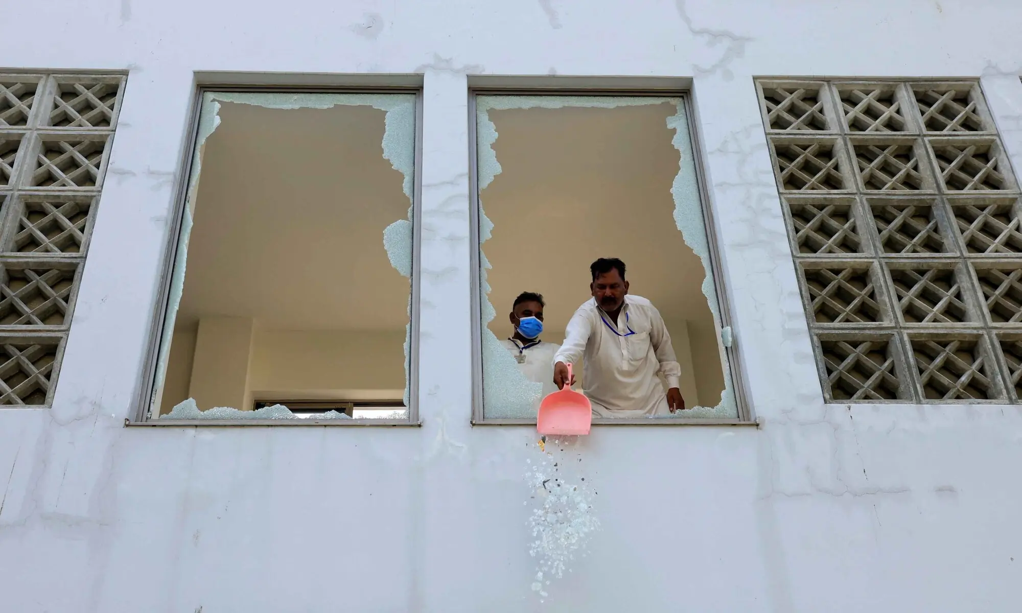 A worker removes broken pieces of a glass window after a fire broke out at the Pakistan Institute of Medical Sciences hospital in Islamabad on Aug 26, 2026. &mdash; Reuters
