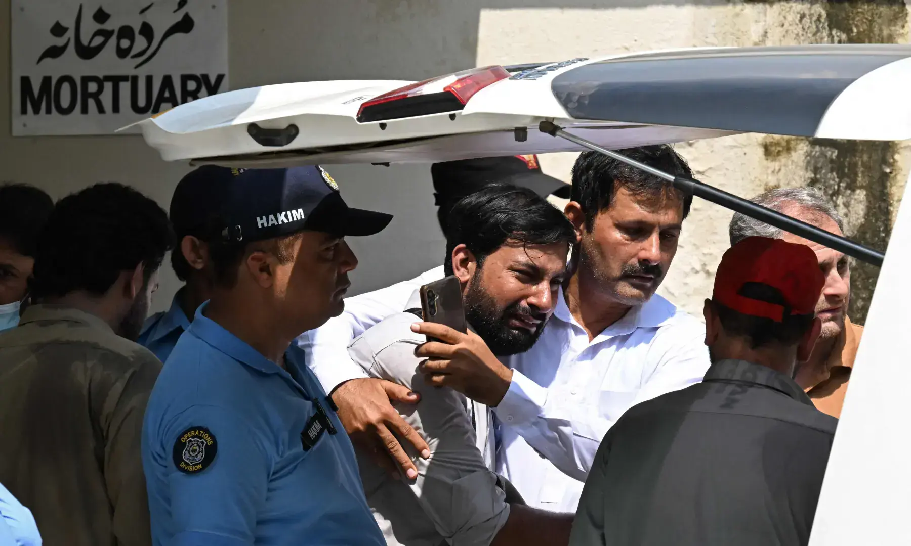 A man consoles a grieving father (C) as his child's coffin is carried after a fire outside the Mother and Child Health (MCH) ward at the Pakistan Institute of Medical Sciences (Pims) hospital in Islamabad on Aug 26, 2026. &mdash; AFP