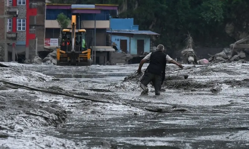 A resident walks along a street covered in mud following flash floods and a landslide disaster in Devighat, in Nepal's Nuwakot district on August 26, 2026. &mdash;AFP