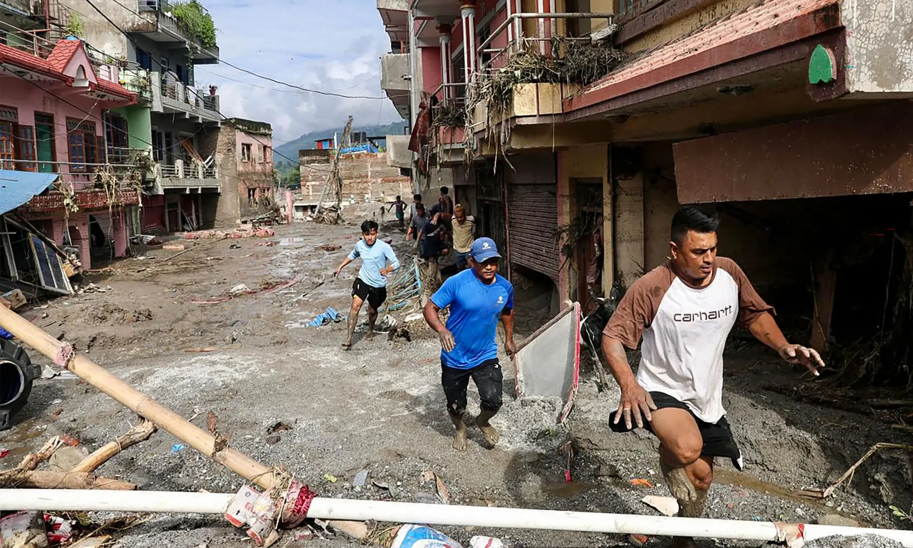 Local residents walk past houses lying deluged in sludge after flash floods at Devighat, Bidur Municipality in Nepal's Nuwakot district on Aug 27, 2026. &mdash; AFP