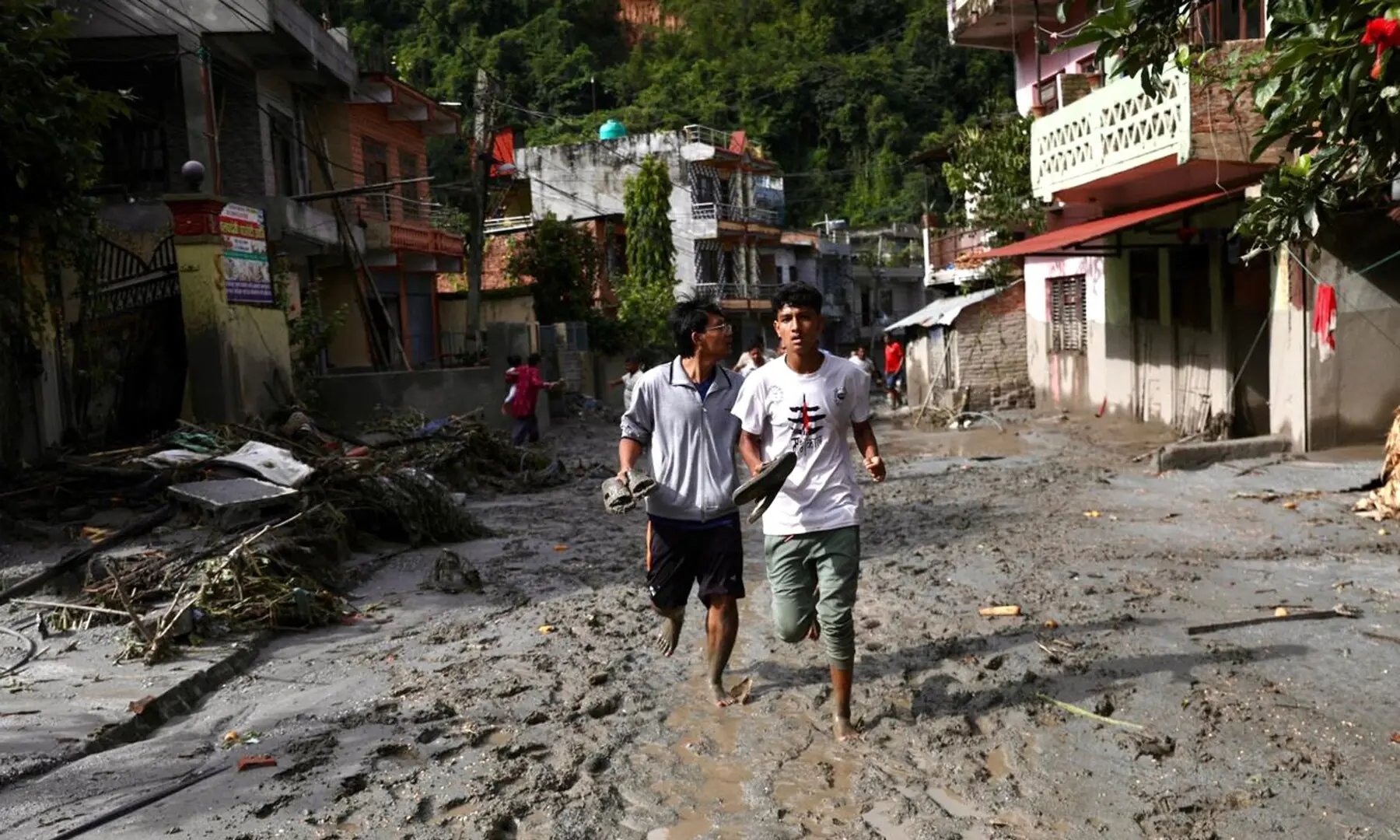 Local residents walk along a street lying deluged in sludge after flash floods near Devighat, Bidur Municipality in Nepal&rsquo;s Nuwakot district on August 27, 2026. &mdash; AFP