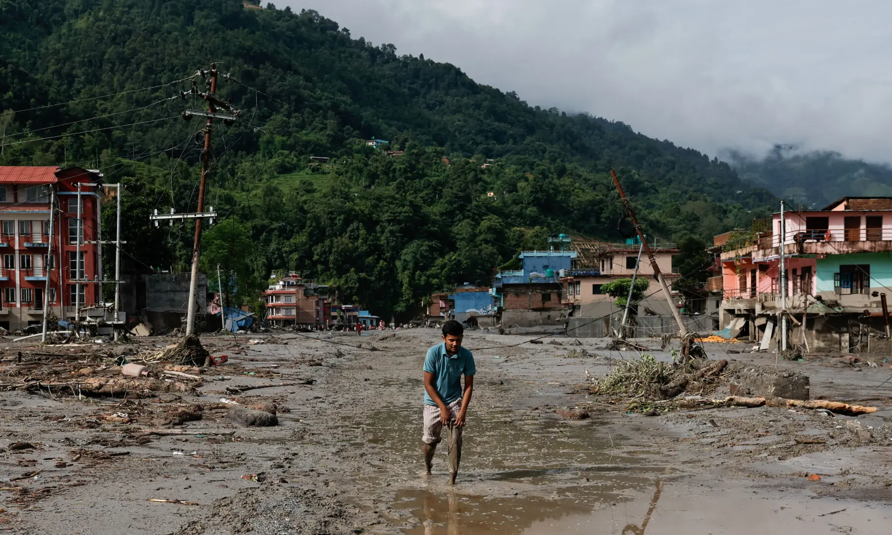 A man wades through muddy waters following devastating floods, in Trishuli in Nuwakot district, Nepal, on Aug 27, 2026. &mdash; Reuters