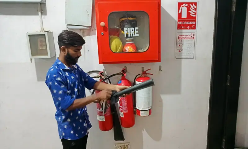 A technician inspects the hose of a fire extinguisher at a multi-storey building.—Shakil Adil / White Star A technician inspects the hose of a fire extinguisher at a multi-storey building.—Shakil Adil / White Star