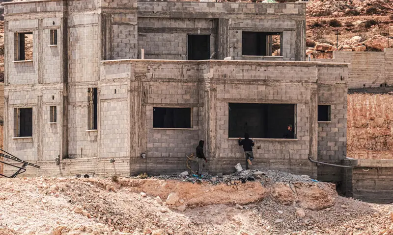 Israeli settlers look at an under-construction Palestinian home in the village of Qusra, occupied West Bank.—AFP Israeli settlers look at an under-construction Palestinian home in the village of Qusra, occupied West Bank.—AFP