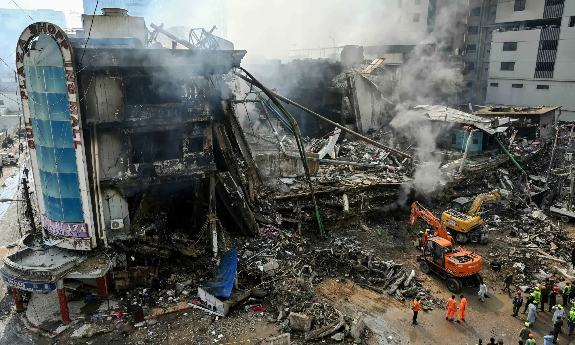 TOPSHOT - Rescue workers search amid the debris using excavators after a massive fire at a shopping mall in Karachi on January 19, 2026. (Photo by Asif HASSAN / AFP) TOPSHOT - Rescue workers search amid the debris using excavators after a massive fire at a shopping mall in Karachi on January 19, 2026. (Photo by Asif HASSAN / AFP)