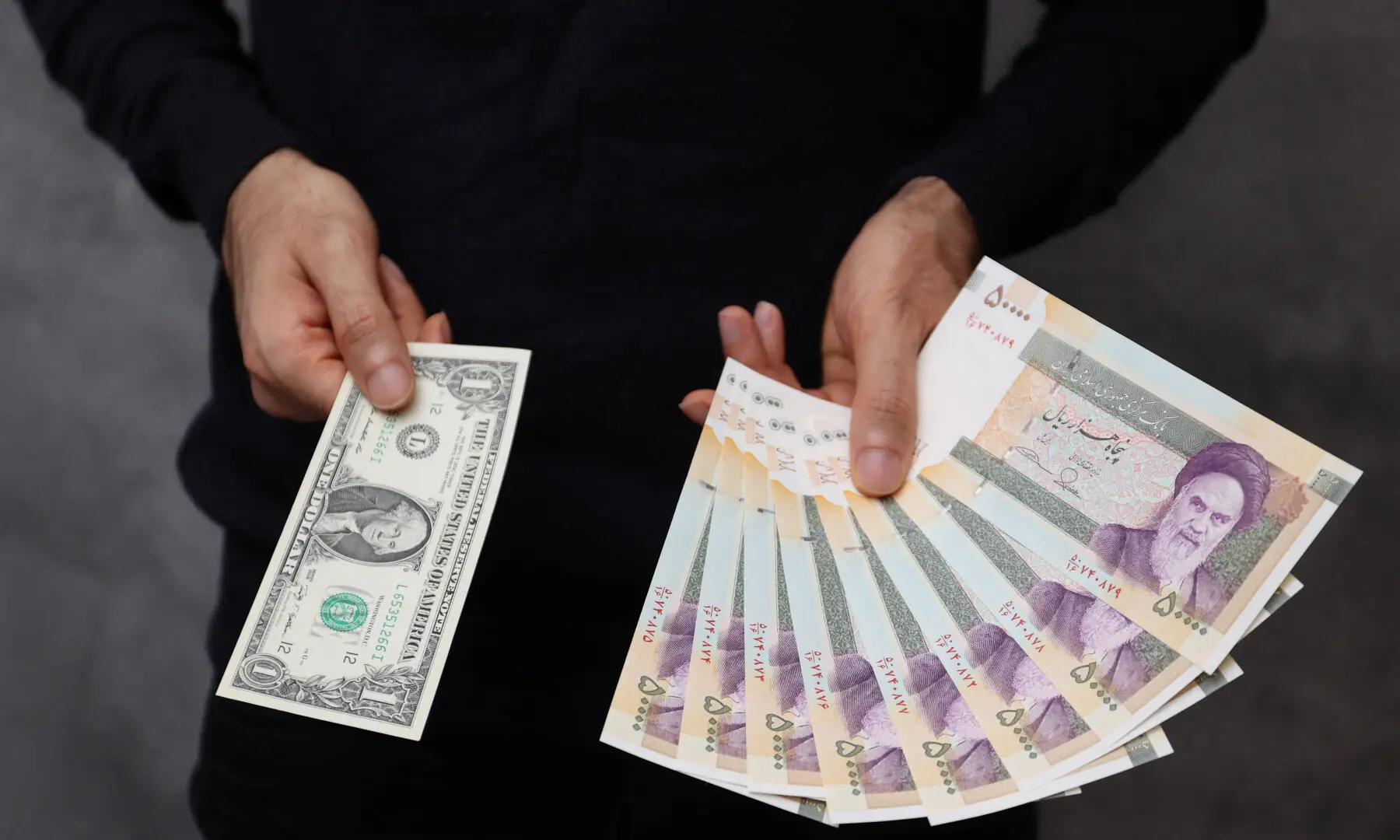 A currency dealer poses for a photo with a US one dollar bill and the amount being given when converting it into Iranian rials in an exchange shop in Tehran, Iran on Dec 25, 2022. &mdash; Wana via Reuters/File