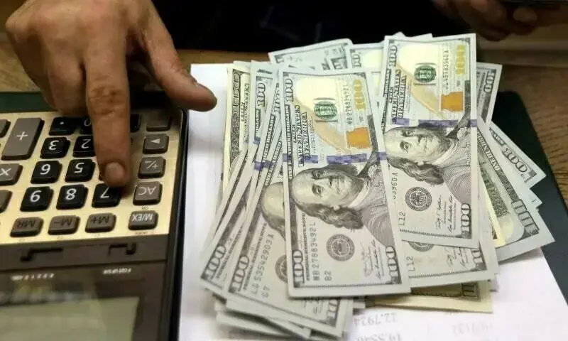A teller at a government office calculates US banknotes. &mdash; Reuters/File
