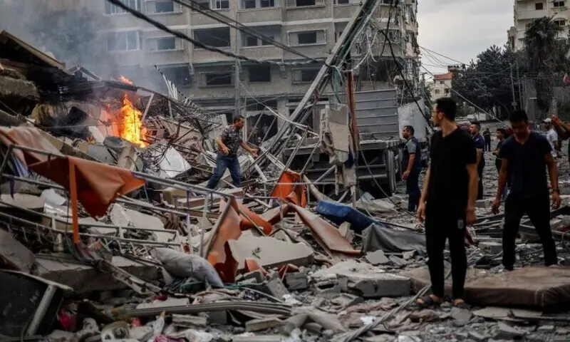 Palestinians watch a fire burn among the rubble of a damaged residential building, in the aftermath of Israeli strikes, in Gaza City, October 10, 2023. &mdash; Reuters/File