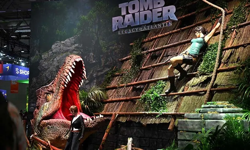 A visitor poses at the Tomb Raider: Legacy of Atlantis booth at the Gamescom video games trade fair on the fair grounds in Cologne, western Germany on August 26, 2026. — AFP