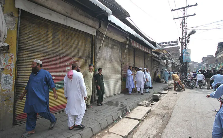 Traders stand outside their shops during a Jamaat-i-Islami rally on Ashraf Road, Peshawar, on Thursday. — White Star Traders stand outside their shops during a Jamaat-i-Islami rally on Ashraf Road, Peshawar, on Thursday. — White Star