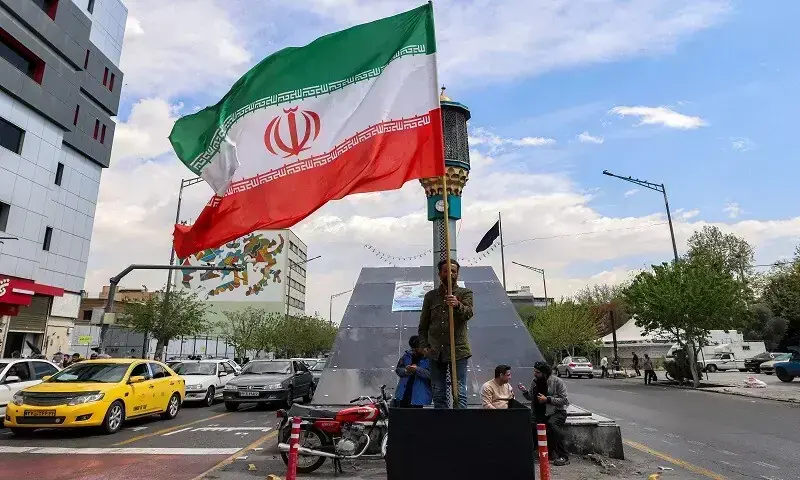 A man stands with an Iranian national flag along an intersection at Valiasr Square in Tehran on April 6, 2026. &mdash; AFP/File