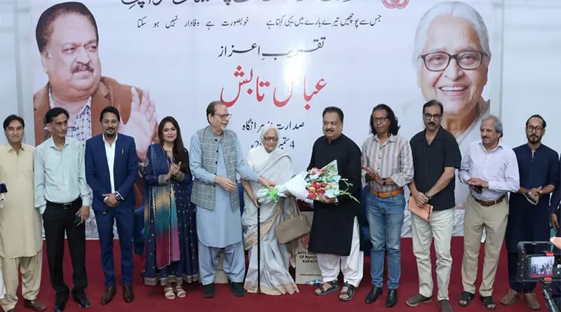 Zehra Nigah and Ahmed Shah present, alongside others, a bouquet to poet Abbas Tabish at the event.&mdash;Dawn