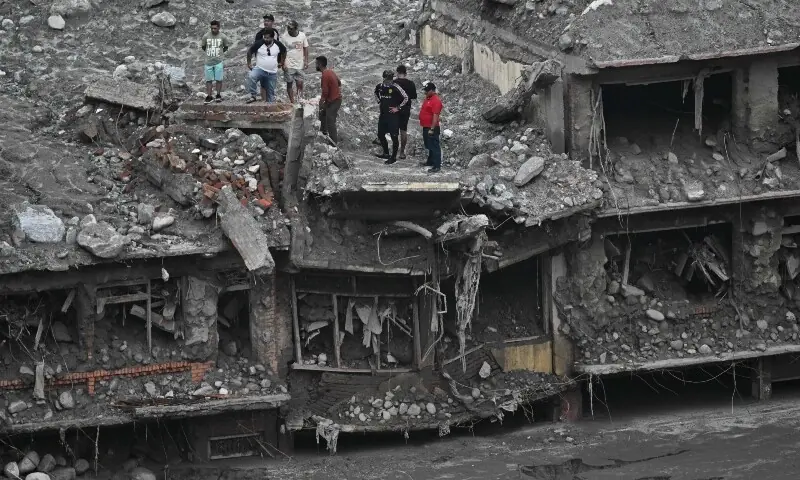 People stand atop damaged houses covered in sludge in the aftermath of flash floods in Trishuli, in Nepal's Nuwakot district on Sept 6, 2026. &mdash;AFP