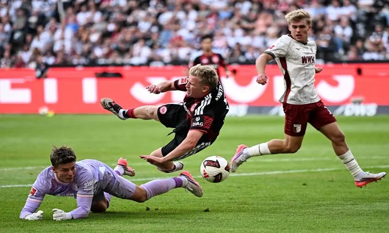 Augsburg goalkeeper Finn Dahmen (L) vies for the ball with Eintracht Frankfurt's Jonathan Burkardt (C) during their Bundesliga match in Frankfurt am Main on September 6, 2026. —AFP Augsburg goalkeeper Finn Dahmen (L) vies for the ball with Eintracht Frankfurt's Jonathan Burkardt (C) during their Bundesliga match in Frankfurt am Main on September 6, 2026. —AFP
