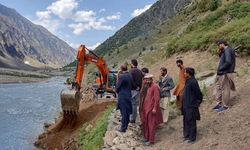 People look on as a machine builds an alternative track along the Kunhar River in Rati Galli area of Kaghan Valley. &mdash; Dawn