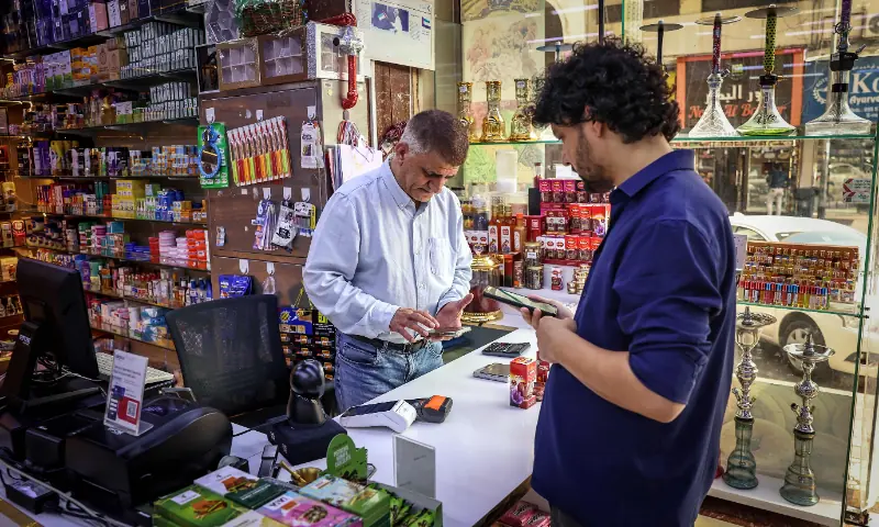 Iranian shop owner Morteza Asaadi (L) attends to a customer at his shop in downtown Bur Dubai on Sept 3, 2026. &mdash; AFP