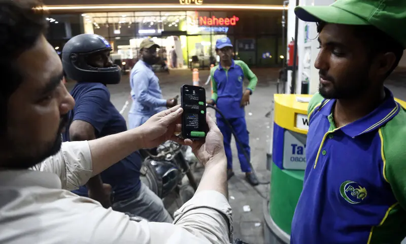 A MAN shows a pump attendant his registration for the fuel subsidy scheme, in Karachi.&mdash;Shakil Adil