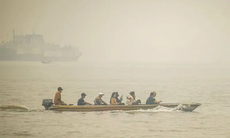 PEOPLE travel on a boat as thick haze from forest and land fires blankets a village in Indonesia’s West Kalimantan region.—AFP PEOPLE travel on a boat as thick haze from forest and land fires blankets a village in Indonesia’s West Kalimantan region.—AFP