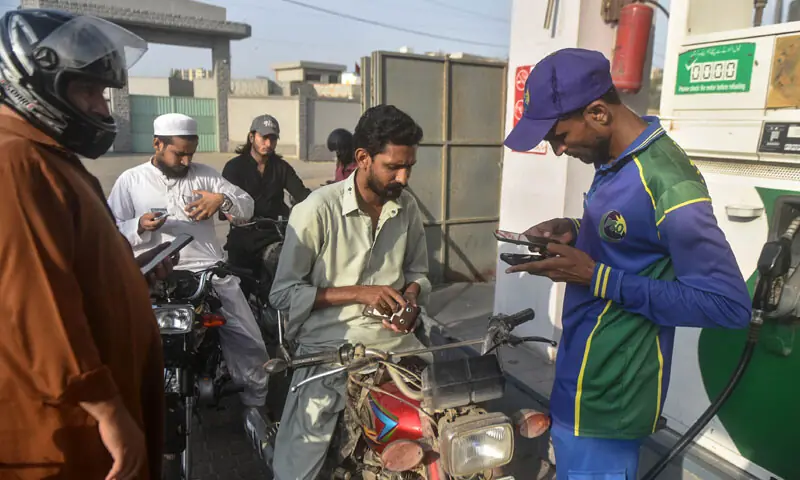 FUEL pump attendants check the token numbers of motorcyclists queuing for subsidised petrol.&mdash;Photo by the writer