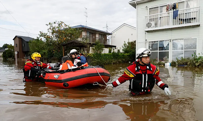 Firefighters transport an elderly woman by boat from a flooded area in Sakura after Typhoon Dujuan brought torrential rain to Japan. &mdash;Reuters