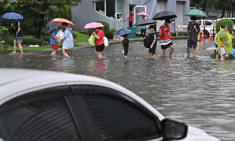 People walk through flood waters along Phetchaburi Road in Bangkok on September 26, 2026. &mdash; AFP