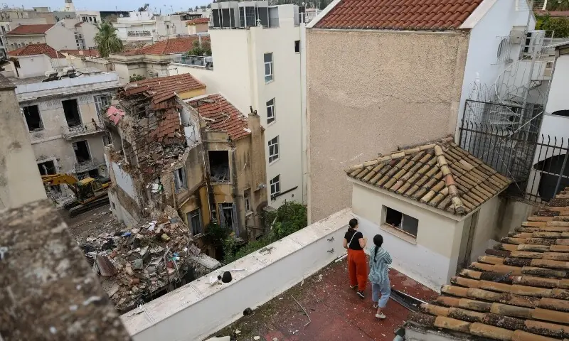 People inspect their building for damage from its rooftop after a neighbouring building partially collapsed following an explosion in the Plaka area, which is popular with tourists, in central Athens, Greece, September 26. &mdash; Reuters