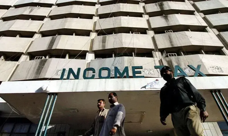 Men walk in front of the income tax building in Karachi. — AFP/File Men walk in front of the income tax building in Karachi. — AFP/File