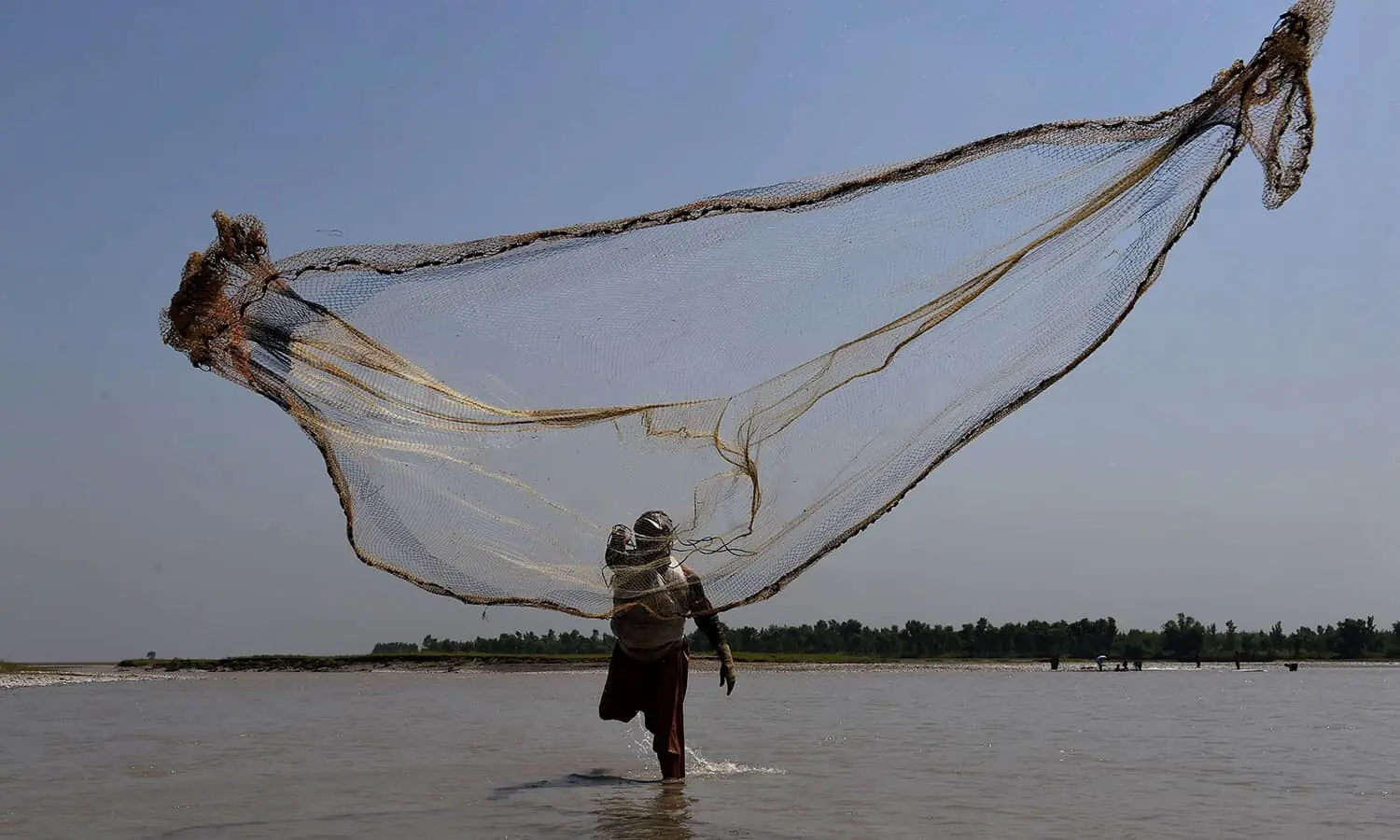 In this photograph taken on August 20, 2016, a Pakistani fisherman casts a net into the River Kabul, at Hajji Zai village in Pakistan's northwestern Charsadda District. --- AFP/File
