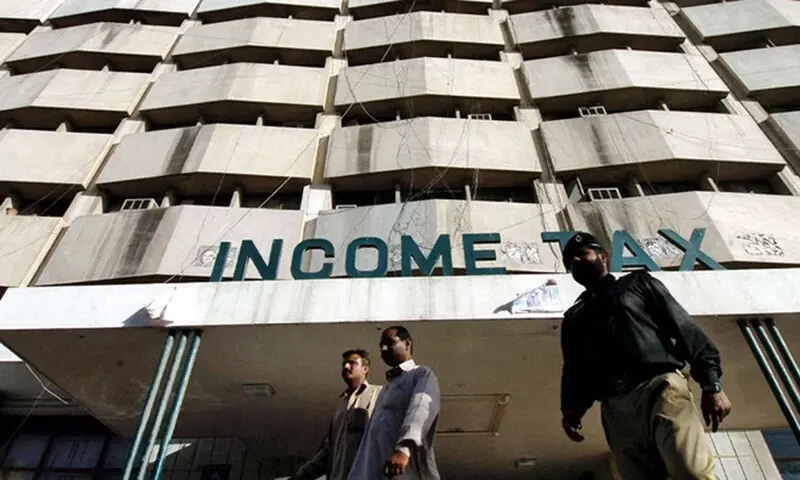 Men walk in front of the income tax building in Karachi. — AFP/File Men walk in front of the income tax building in Karachi. — AFP/File