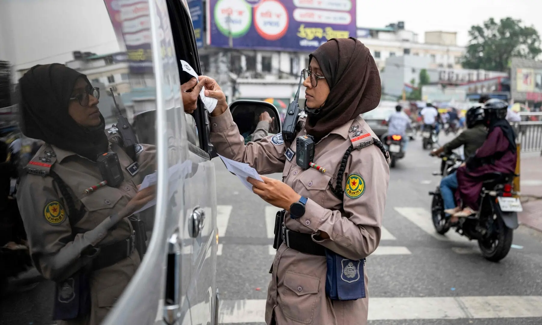 This photograph taken on September 16, 2026 shows Nipa Khatun, a traffic sergeant issuing a traffic violation ticket to a driver in Dhaka. &mdash;AFP