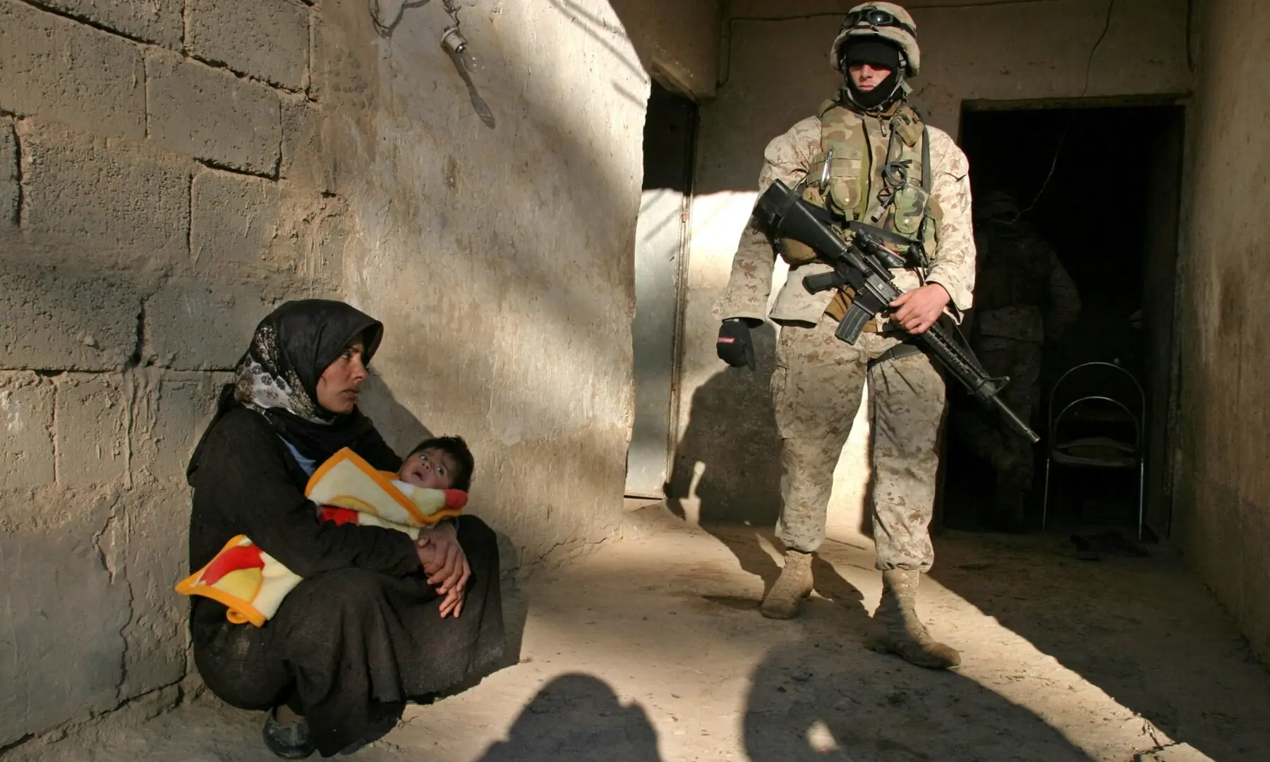 A US Marine watches a woman and her child during a series of raids to hunt arms and guerrilla suspects south of Baghdad, Iraq on December 1, 2004. &mdash;Reuters/File