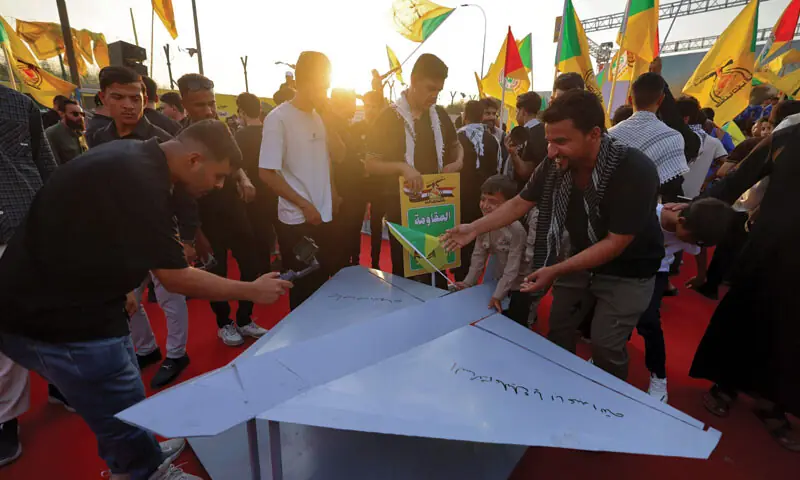 BAGHDAD: People gather around a mock Iranian drone as they celebrate the withdrawal of US forces from Iraq.—AFP BAGHDAD: People gather around a mock Iranian drone as they celebrate the withdrawal of US forces from Iraq.—AFP