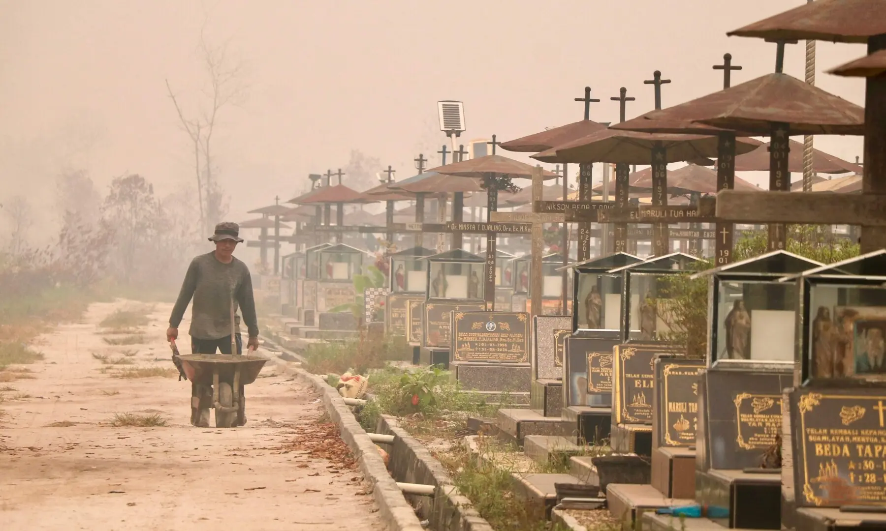 A worker pushes a wheelbarrow through a public cemetery blanketed in thick smoke haze caused by forest and land fires in Palangka Raya, Central Kalimantan province on September 30, 2026. &mdash;AFP