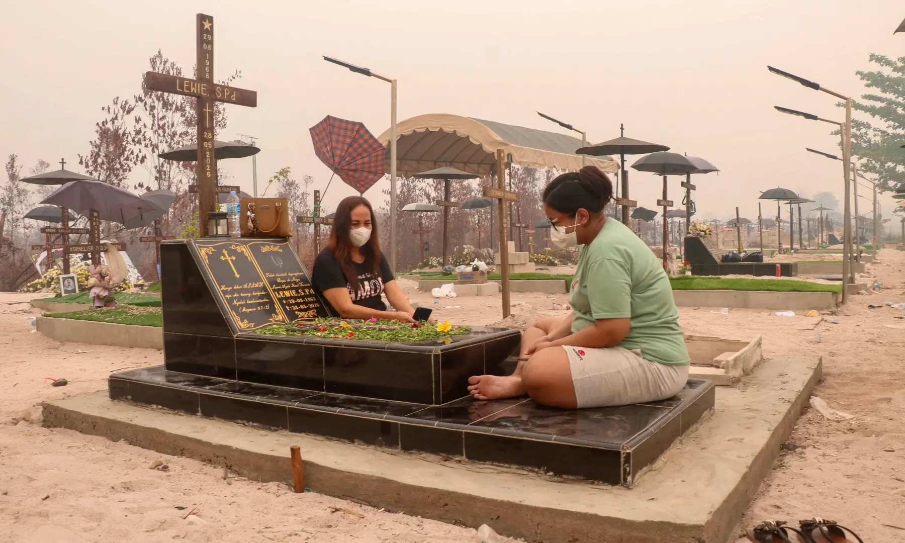 Visitors pay respect to loved ones at a public cemetery shrouded in thick smoke haze caused by forest and land fires in Palangka Raya, Central Kalimantan province on September 30, 2026. &mdash;AFP