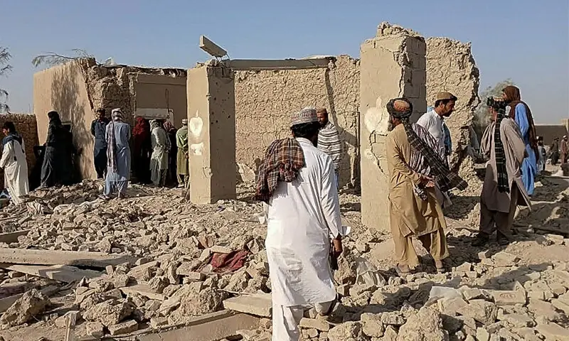 LOCALS and Afghan Taliban gather near destroyed structures following an air strike in Helmand province.—AFP LOCALS and Afghan Taliban gather near destroyed structures following an air strike in Helmand province.—AFP