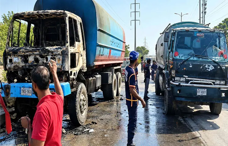 Rescue workers stand around the tanker after it was set on fire by a mob near Singer Chowrangi in Korangi.—PPI Rescue workers stand around the tanker after it was set on fire by a mob near Singer Chowrangi in Korangi.—PPI