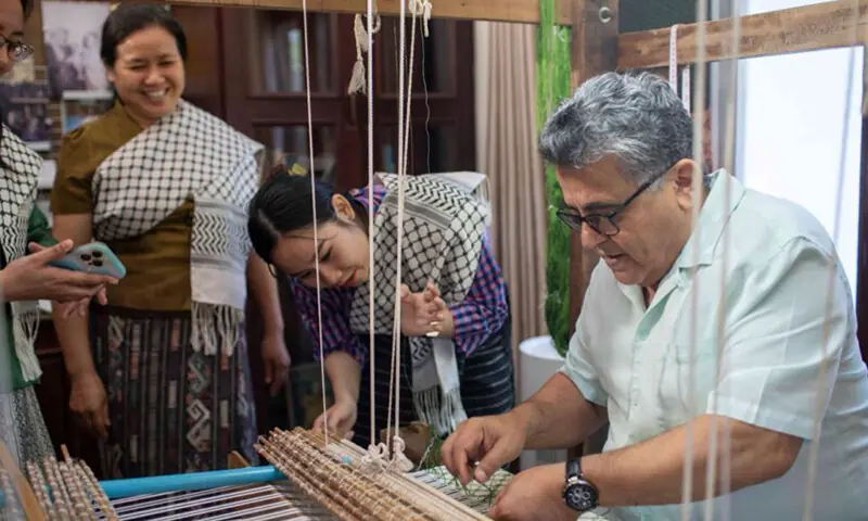 Palestinian ambassador Saadi Salama weaves a few lines of the silk keffiyeh at the residency in Vientiane.&mdash;ANN