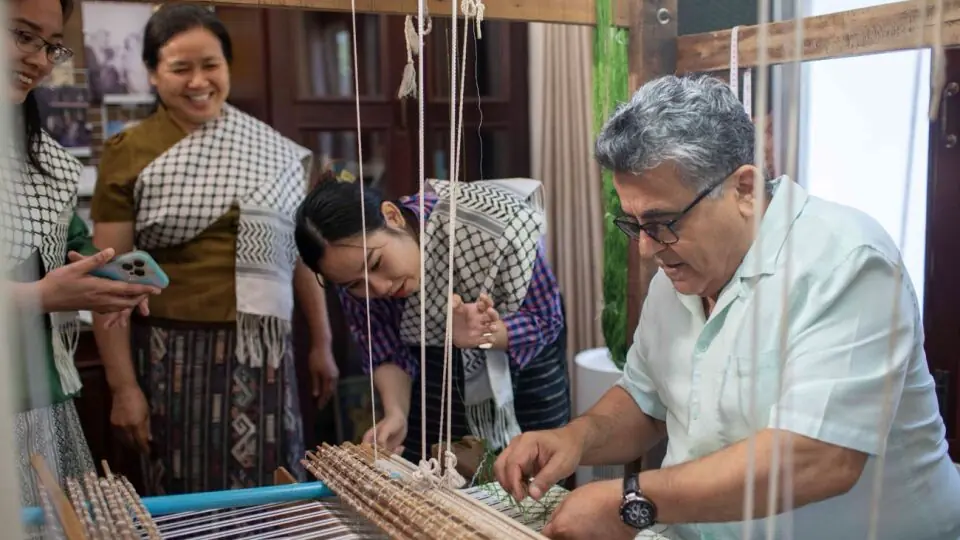 Palestinian ambassador Saadi Salama weaves a few lines of the silk keffiyeh at the residency in Vientiane.