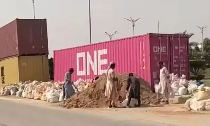 ATTOCK: Workers fill bags with sand, to be placed inside containers brought to block the path of PTI marchers.—Dawn ATTOCK: Workers fill bags with sand, to be placed inside containers brought to block the path of PTI marchers.—Dawn