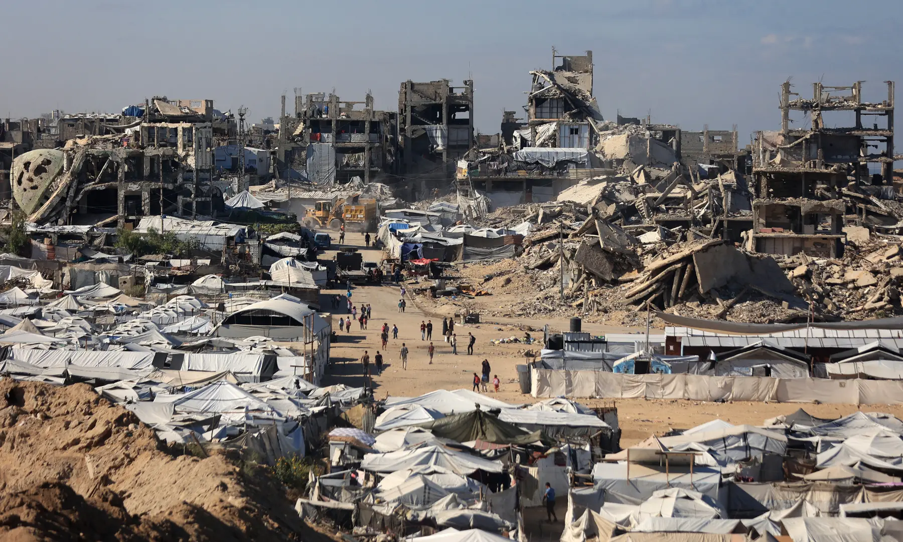 Displaced Palestinians walk amid their temporary tents near destroyed buildings in Gaza City on October 7, 2026. &mdash; AFP