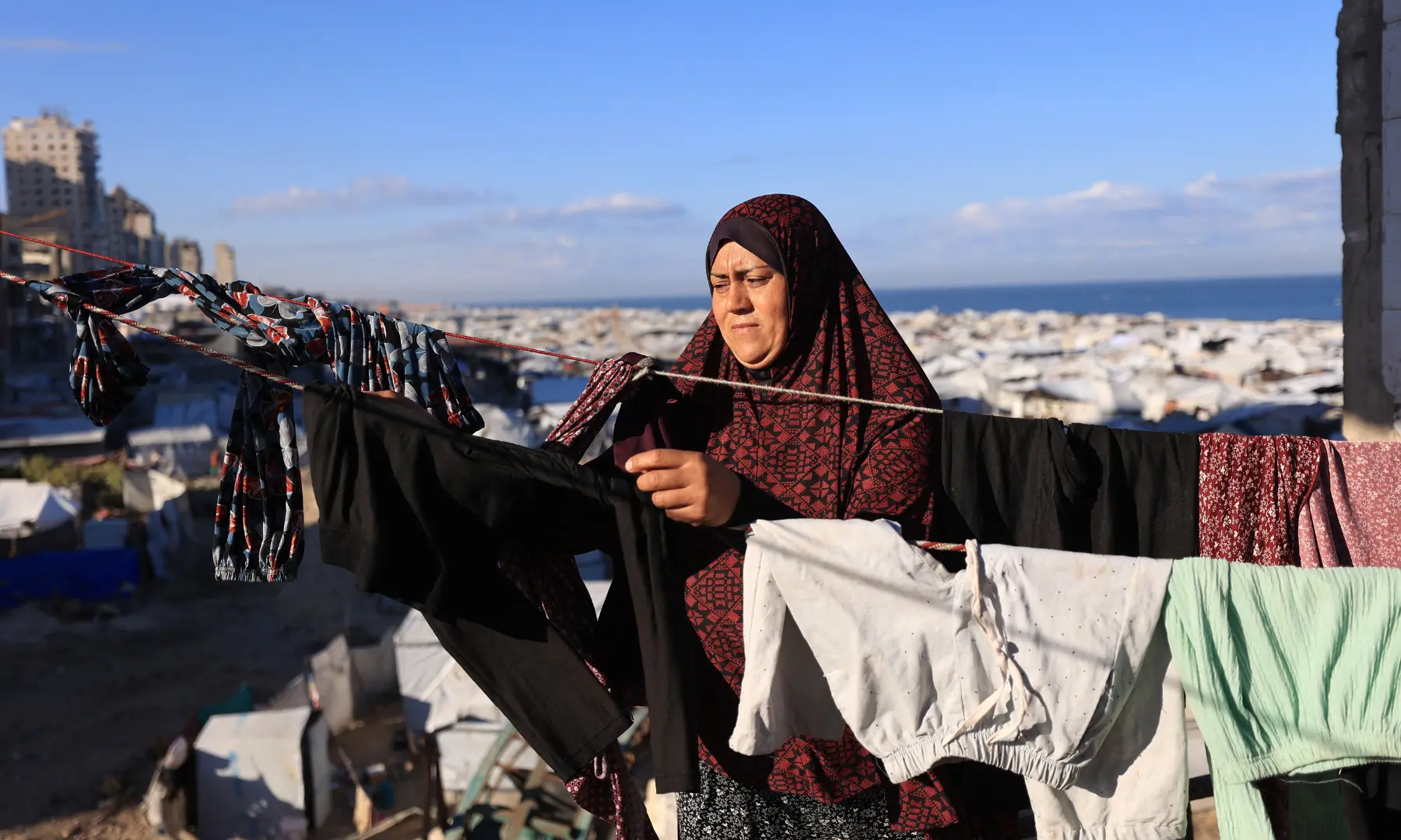 A displaced Palestinian woman hangs her clothes for drying, in Gaza City on Oct 7, 2026. &mdash; AFP