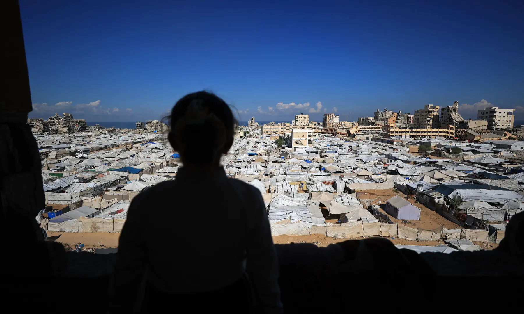 A girl looks at the temporary tents of displaced Palestinians along destroyed buildings in Gaza City on Oct 7, 2026. &mdash; AFP