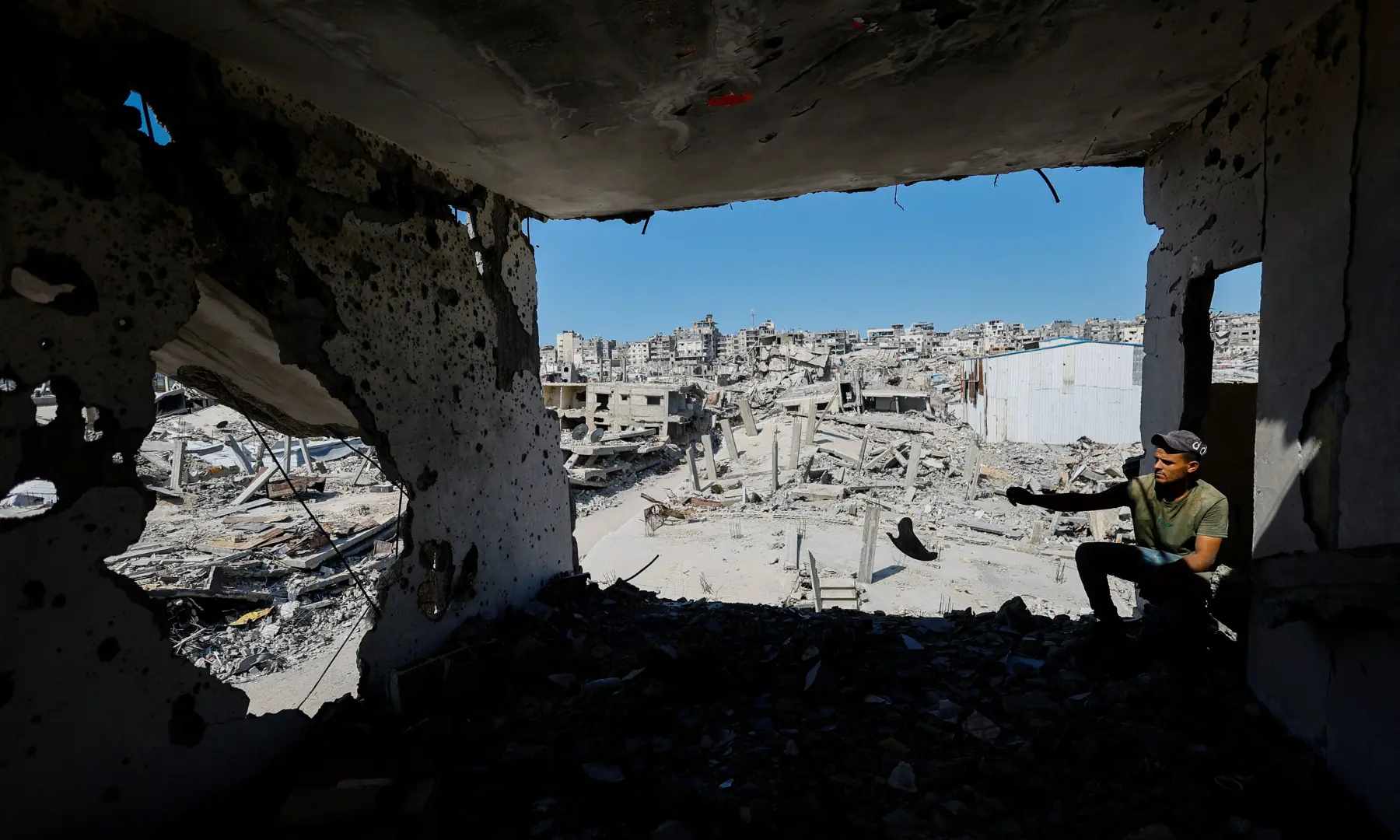 A Palestinian sits in the ruins of a building destroyed during the war, in Gaza City, on Oct 7, 2026. &mdash; Reuters