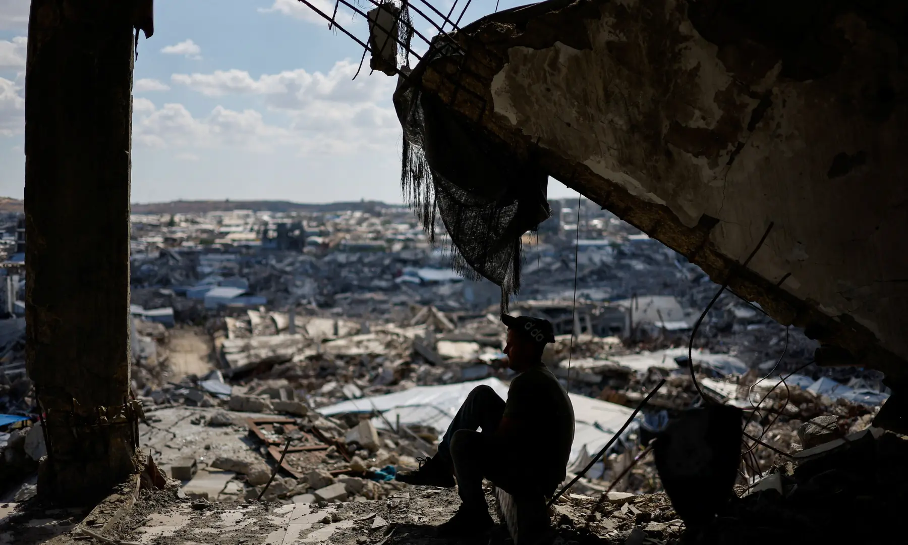 A Palestinian sits in the ruins of a building destroyed during the war, in Gaza City, on Oct 7, 2026. &mdash; Reuters