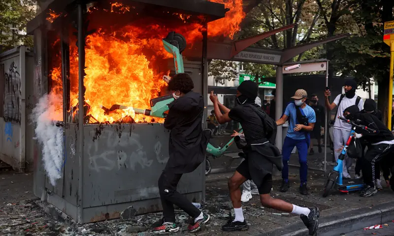 Liege (Belgium): Demonstrators try to put an electric scooter into a burning structure on a street during a protest by high school students against education reforms and an increase in fees.—Reuters Liege (Belgium): Demonstrators try to put an electric scooter into a burning structure on a street during a protest by high school students against education reforms and an increase in fees.—Reuters